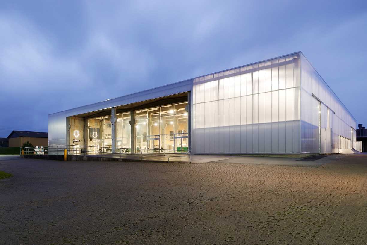 Nærbillede af stor bygning med glas facade. Der er lys inde i bygningen.