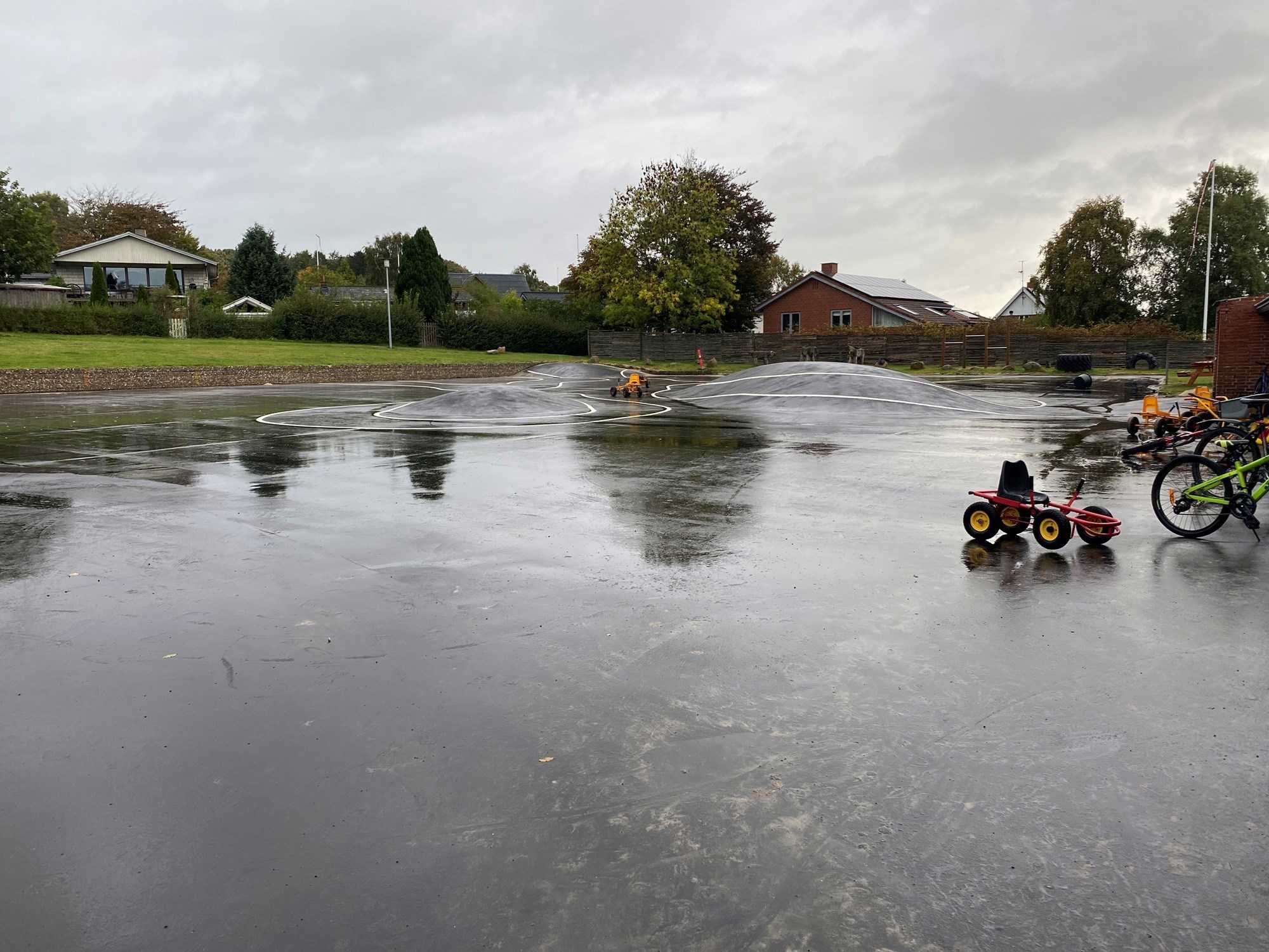 Asfaltplads med optegnet bane, cykler og børnekøretøjer.