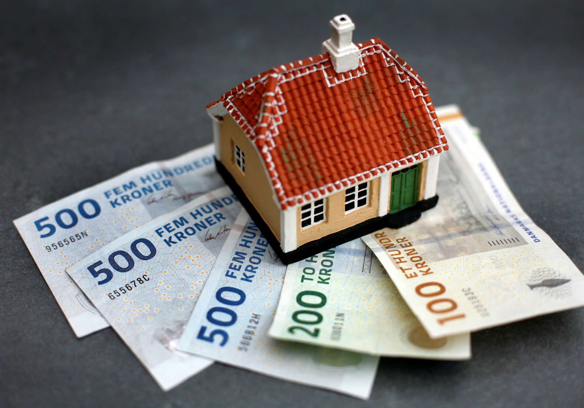 Pengesedler med lille legetøjshus på