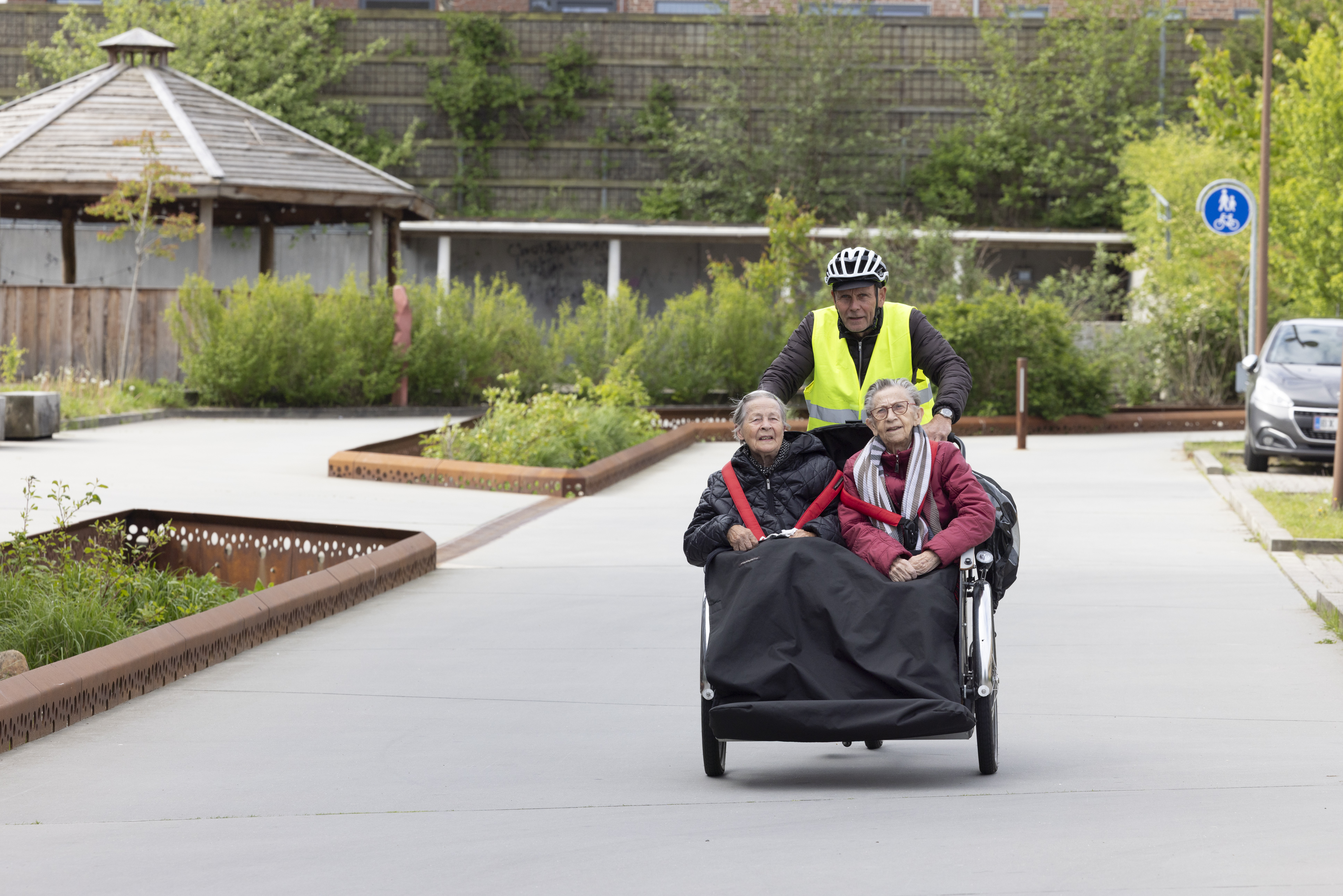 Frivillig cykler med to borgere