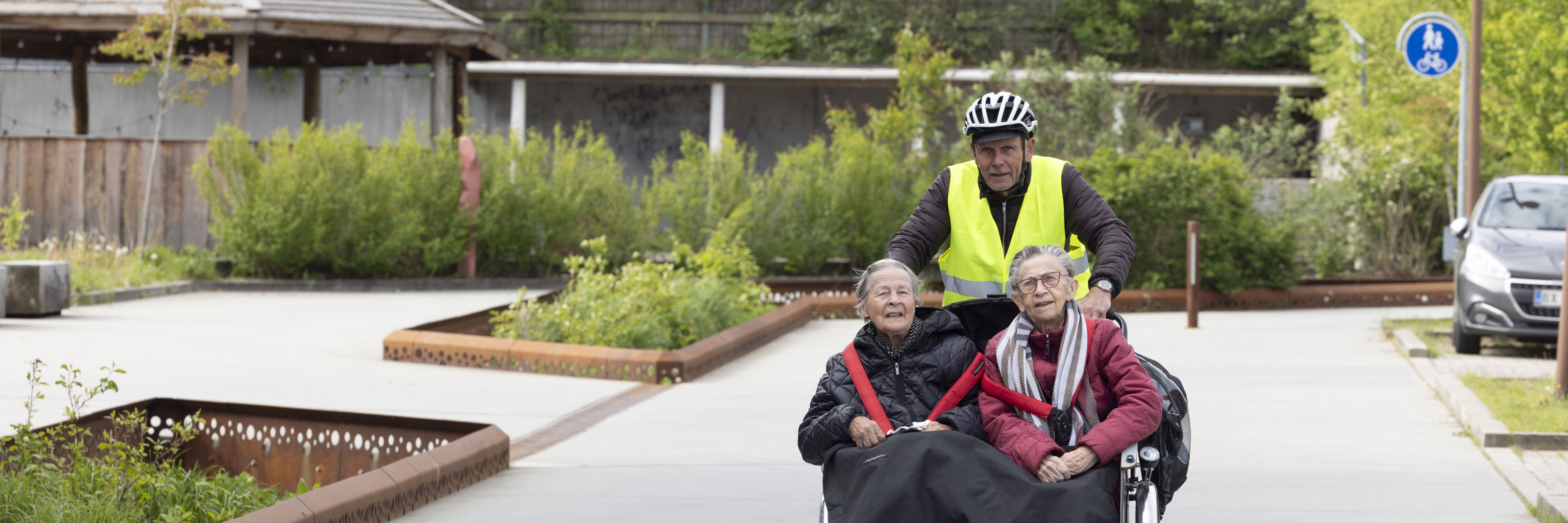 Frivillig cykler med to borgere
