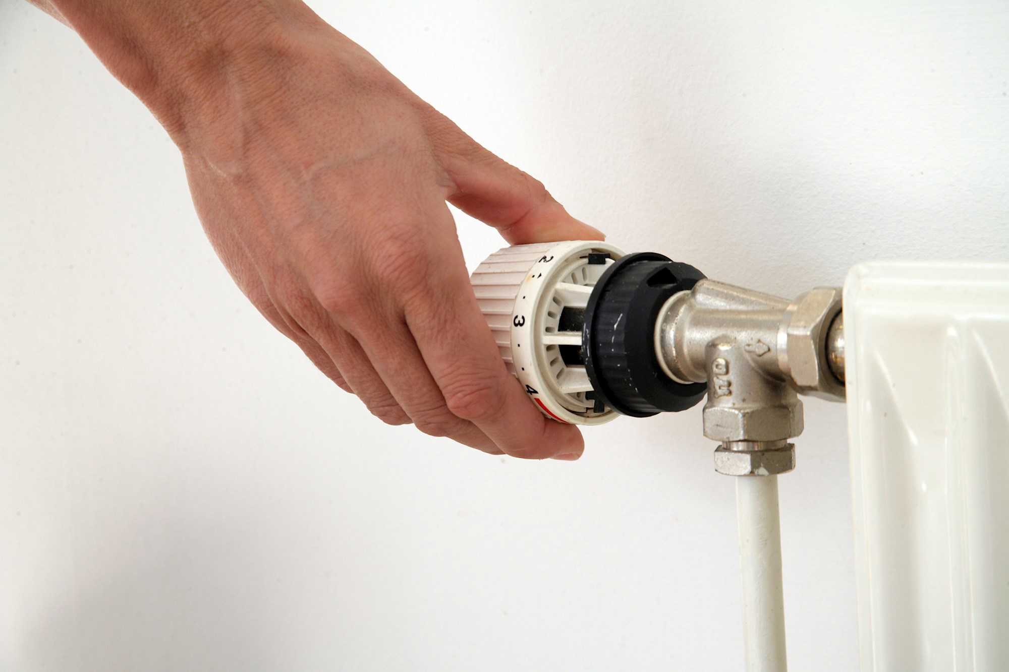 En hånd drejer på en termostat på en radiator