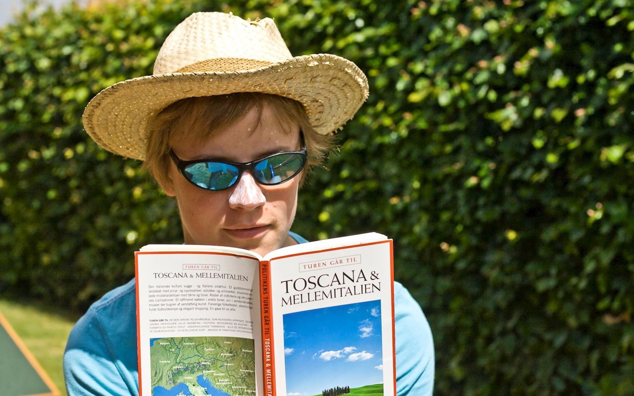 Kvinde læser rejseguide i solskin